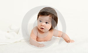 Adorably baby lie on towel in bed, white background. Happy childhood and healthcare concept. Yellow toned