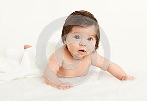 Adorably baby lie on towel in bed, white background. Happy childhood and healthcare concept. Yellow toned