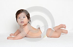 Adorably baby lie on white towel in bed. Happy childhood and healthcare concept