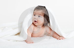 Adorably baby lie on white towel in bed. Happy childhood and healthcare concept