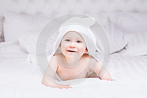 Adorably baby lie on white towel in bed. Happy childhood and healthcare concept.