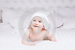 Adorably baby lie on white towel in bed. Happy childhood and healthcare concept.