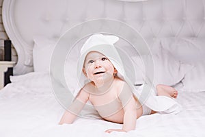 Adorably baby lie on white towel in bed. Happy childhood and healthcare concept.