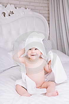 Adorably baby lie on white towel in bed. Happy childhood and healthcare concept.