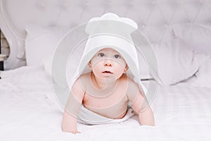 Adorably baby lie on white towel in bed. Happy childhood and healthcare concept.