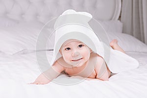 Adorably baby lie on white towel in bed. Happy childhood and healthcare concept.