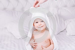 Adorably baby lie on white towel in bed. Happy childhood and healthcare concept.