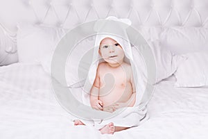 Adorably baby lie on white towel in bed. Happy childhood and healthcare concept.