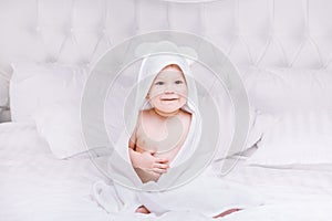 Adorably baby lie on white towel in bed. Happy childhood and healthcare concept.