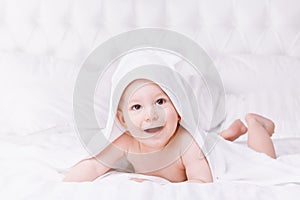 Adorably baby lie on white towel in bed. Happy childhood and healthcare concept.