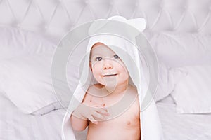 Adorably baby lie on white towel in bed. Happy childhood and healthcare concept.