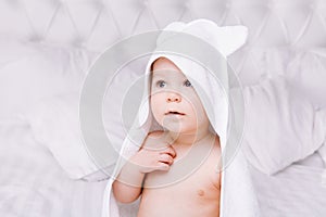 Adorably baby lie on white towel in bed. Happy childhood and healthcare concept.