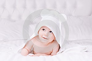 Adorably baby lie on white towel in bed. Happy childhood and healthcare concept.