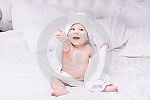 Adorably baby lie on white towel in bed. Happy childhood and healthcare concept.