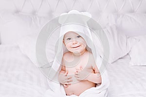 Adorably baby lie on white towel in bed. Happy childhood and healthcare concept.