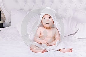 Adorably baby lie on white towel in bed. Happy childhood and healthcare concept.