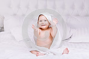 Adorably baby lie on white towel in bed. Happy childhood and healthcare concept.