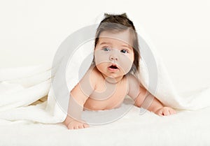 Adorably baby lie on white towel in bed. Happy childhood and healthcare concept. Yellow toned