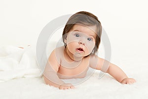 Adorably baby lie on white towel in bed. Happy childhood and healthcare concept. Yellow toned