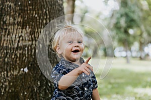 Adorable šťastný a roztomilý malý kaukazský batoľa dieťa chlapec dlho vlasy usmievavý, a beh mimo v zelený 