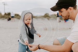 Adorable perfektné mladý a dieťa batoľa syn rodina zabávajúci sa na piesočnatý pláž počas západ slnka mimo podľa oceán 