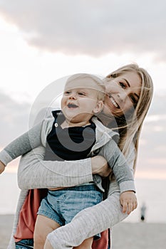 Adorable perfektné mladý matka a dieťa batoľa syn rodina usmievavý, a držanie jeden ďalšie na piesočnatý pláž počas slnko 