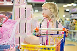 Adorble girl with small shopping cart in kids mall