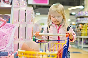 Adorble girl with small shopping cart in kids mall