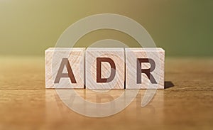 ADR abbreviation for Adverse Drug Reaction word written on wooden blocks on a wooden table. Medical concept