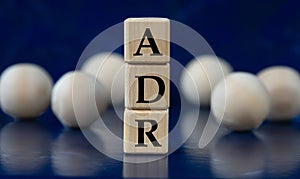 ADR - acronym on wooden cubes on a blue background with wooden balls