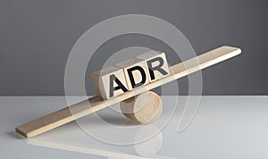 ADR on wooden cubes on a wooden balance , business concept