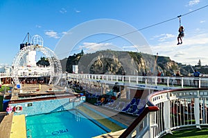 A young boy riding a zip line high above the pool deck of a cruise liner