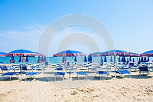 Adriatic Sea coast view. Seashore of Italy, summer umbrellas on sandy beach with clouds on horizon.