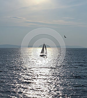 Adriatic Sea with a sailing ship on it under sunlight and a cloudy sky in Croatia