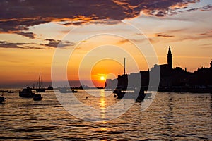 Adriatic sea with some boats sailing and the view of the croatian houses of Rovinj, Croatia, and the bell tower of the Church of