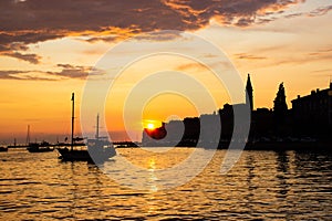 Adriatic sea with some boats sailing and the view of the croatian houses of Rovinj, Croatia, and the bell tower of the Church of