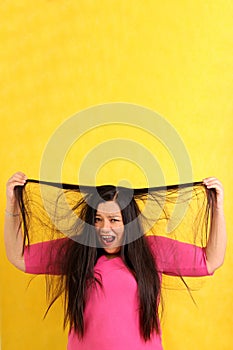 Adult 40-year-old Latina woman ruffles her hair desperate with anxiety and frustration with very long straight damaged hair