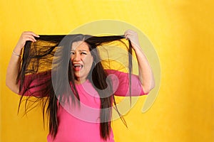 Adult 40-year-old Latina woman ruffles her hair desperate with anxiety and frustration with very long straight damaged hair