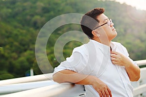 Adult Asian Fat man in white shirt feeling despondent from hard work be finding relaxing and meditation by make calm on the side photo