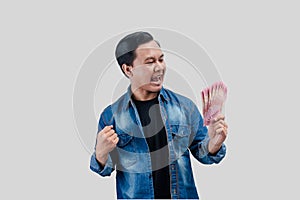 Adult Asian man clenched fist while holding paper money