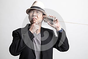 Adult Asian man  hearing with tin can phone and thinking