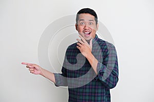 Adult Asian man pointing to the right with wow face expression photo