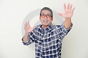 Adult Asian man showing excited expression when trying to grab something that fall from above