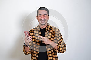 Adult Asian man showing happy expression while pointing to his mobile phone photo
