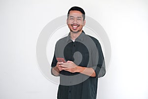 Adult Asian man showing happy face expression when holding his mobile phone photo