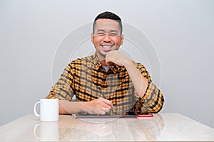Adult Asian man smiling confident in the tabel when working using mobile tablet and handphone photo