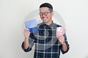 Adult Asian man smiling happy when looking to his bank saving book