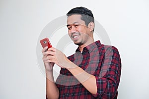 Adult Asian man smiling happy when looking to his mobile phone photo