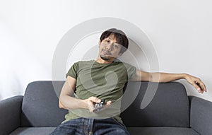 Adult asian man watching television sitting on couch at home.