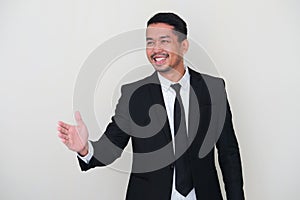 Adult Asian man wearing black suit and tie doing hand shake gesture for agreement